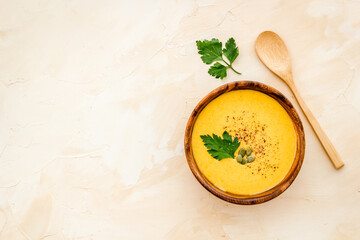 Pumpkin soup on beige background top view copy space