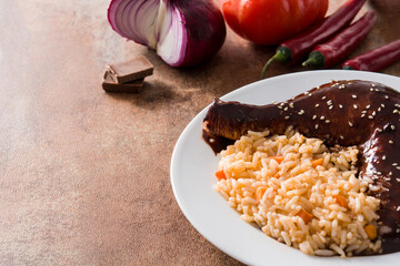 Traditional mole Poblano with rice plate on rusty surface. Copy space