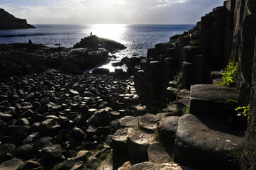 Vue sur les colonnes basaltiques hexagonales, la mer bleue et les gens marchant sur la chaussée...