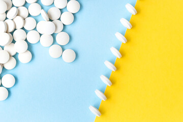 Yellow sky blue background, a scattering of pills, pills in a row stand. Bright, conceptual, diagonal. Health care, medicines. Pills against viruses, depression, headache. View from above.