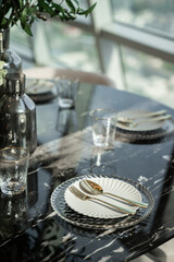 Home Inerior with dining room table setting with gold stainless tableware and cutlery setting on nartual marble top / interior design