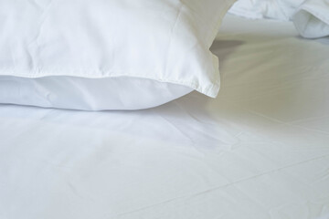 Close-up of clean white soft pillow on the comfortable bed in the bedroom.