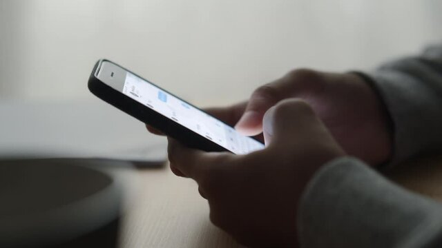 Side view. Hand of girl using smartphone at home, typing message Close-up 
