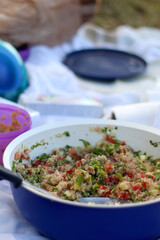 Big bowl of quinoa, tomato, cucumber and parsley salad, served on a picnic. Selective focus.