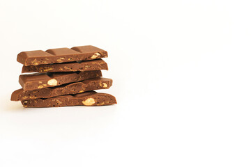 Chocolate slices are stacked on a white background.Dark chocolate with nuts.