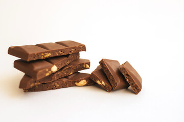 Chocolate slices are stacked on a white background.Dark chocolate with nuts.