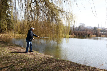 Senior man fishing on lake in spring