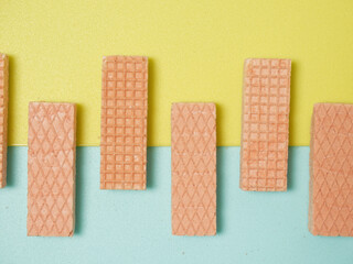 Pink Wafer biscuits in a pattern and shape on a yellow and blue background with space for copy