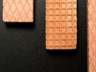 Pink Wafer biscuits in a pattern and shape on a black background with space for copy