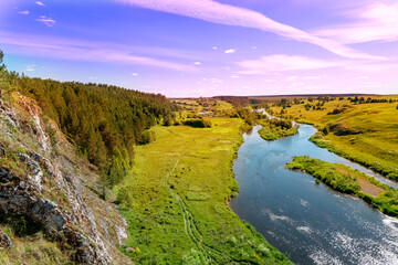 Fototapeta na wymiar summer sunset over the river and forest. beautiful view from a cliff to a river with islands and a shore with young green grass