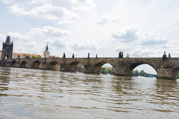 Fototapeta premium Charles Bridge in Prague in the center of Prague and the flowing Vltava River in summer and there are clouds in the sky