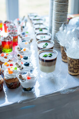 Sweet cakes in cups at a wedding buffet. Candy bar catering