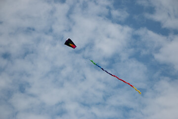 Red, green, blue, yellow colorful isolated kite with blue sky and clouds.
