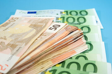 stack with 50 euros on the background of banknotes of 100 euros. Close-up. Financial concept. Blue background.