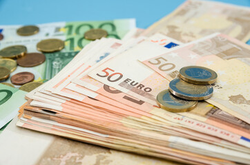 stack with 50 euros and coins. Blue background. Close-up. Financial concept. A lot of euro banknotes.