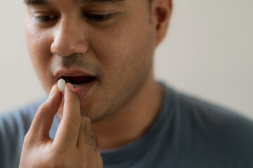 Fototapeta na wymiar Close up handsome man taking pill. Medicine, health care concept.