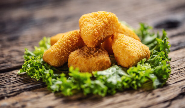 Cheese nuggets on top of salad leaf placed on a rustic wood