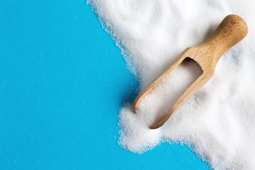 Salt grain in wooden spoon top view on a blue background , flat lay.