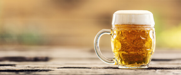 Beer mug with a fresh draft beer on an outddor table