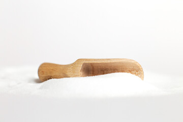 Salt grain in wooden spoon top view on a white background , flat lay.