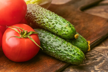 Fresh vegetables, tomatoes and cucumbers on a wooden cutting board. ingredients to prepare healthy meals