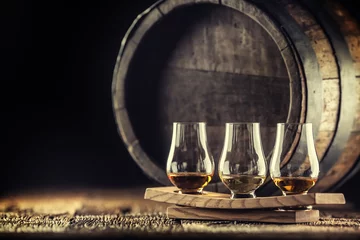 Fotobehang Glencairn whiskey tasting cups on a wooden serving, with a whisky barrel in the dark background © weyo