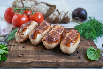 grilled sausages with tomatoes and herbs on the board on white table