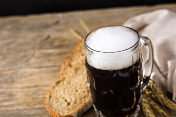 Traditional kvass beer mug with rye bread on wooden table. Copy space	