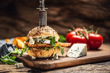 Chicken burger with blue cheese and arugula in a sesame bun on a rustic wood