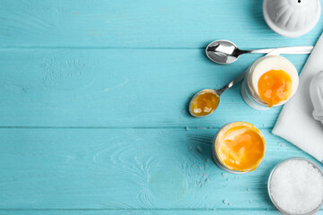 Soft boiled chicken eggs served on light blue wooden table, flat lay. Space for text