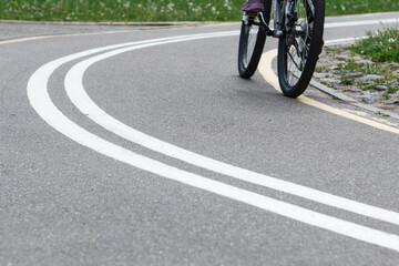 Woman riding a bike on bike path with markings in park