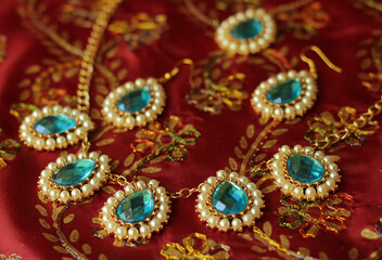 Indian female jewelry in gold and blue on a red background. 