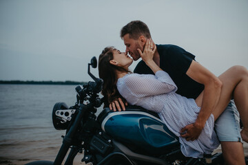 Couple makes love on beach lying on motorcycle.