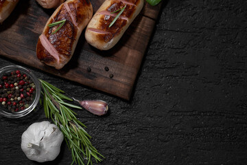 grilled sausages with herbs on the board on a wooden table with copy space