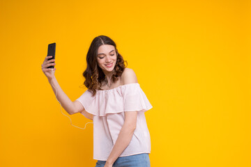 Portrait summer stylish cute curly brunette woman in headphones,holding mobile phone,dancing...