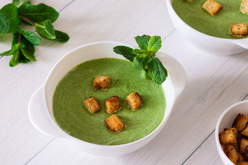 Delicious fresh cream soup of young peas and mint with croutons made of white bread, healthy food