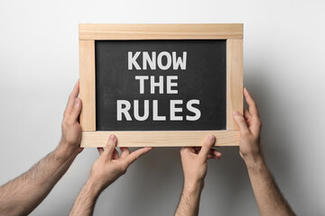 Men holding chalkboard with phrase Know the rules on white background, closeup