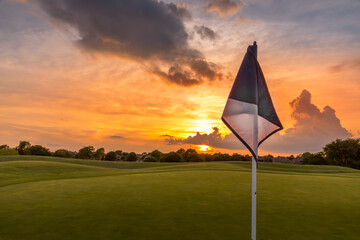 Sunset sky over the fairway of a golf course in Texas with a golf flag in the foreground