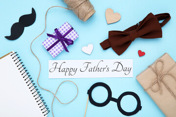 Text Happy Father's Day with notepad, gift boxes, paper mustache and eyeglasses on blue background