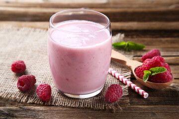 Raspberry smoothie in glass with straw on brown wooden table