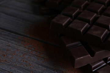 Tasty dark chocolate bars on wooden table. Space for text