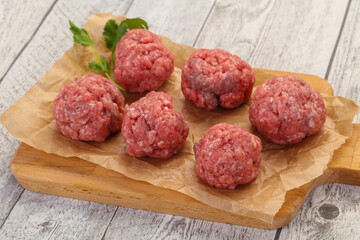 Raw meatball over wooden background