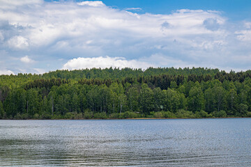 The landscape of mountain lake wit wavy blue water and green forest on a cloudy weather summer day. Travel, tourism, and resort in nature concept. Vlasina lake, Serbia, Europe.