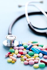 Colorful pills with stethoscope on blue background