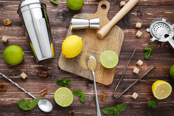 Barman equipments with limes, lemons and sugar on brown wooden table