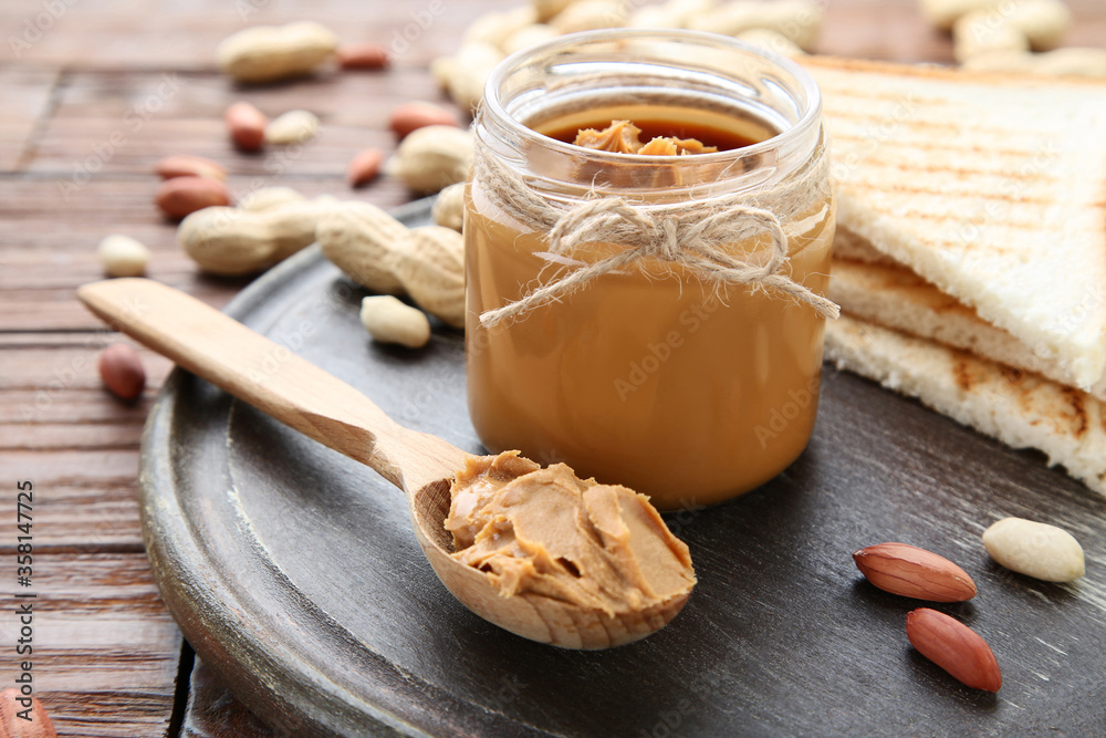 Poster Peanut butter with bread and nuts on wooden table