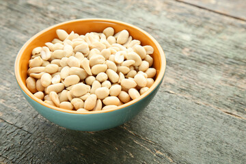 Peanuts in bowl on grey wooden table