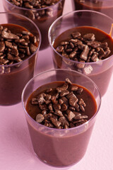 acrylic cups with brigadeiro and chocolate sprinkles on lilac background