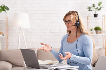 Questions in online meeting at home. Woman with headset gesticulation and answering online