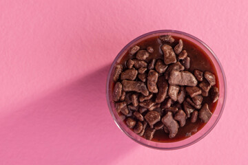 acrylic cup with brigadeiro and chocolate sprinkles on pink background